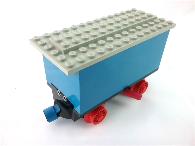 Lego Train Battery Box Car with Two Contact Holes, Red Switch Lever, Blue and Red Magnets, Red Wheels, and Light Gray Roof